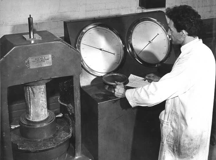 Concrete testing: technician measures force required for failure of concrete cylinder
