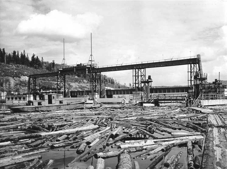 Moving logs towards the Rapide-Blanc Dam`s log chute