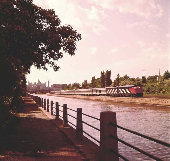 Passenger train leaving Ottawa Union Station beside Rideau Canal