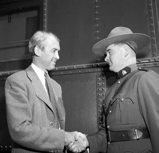 While filming in the Rockies, actor James Stewart greets a mountie