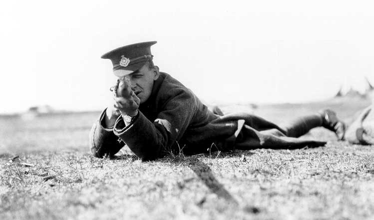 A soldier, at a WWI training camp, preparing to shoot