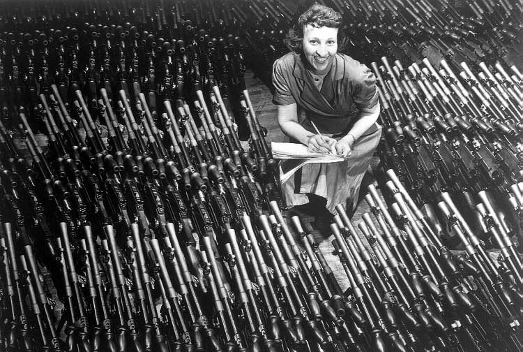 A female worker sitting amongst Bren machine guns in the Ordnance Plant at the John Inglis Co.