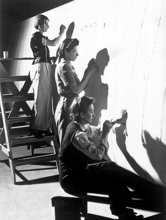 Women workers sewing a fabric-covered airplane wing