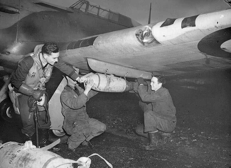RCAF ground crew load a bomb under the wing of a Hurricane bomber