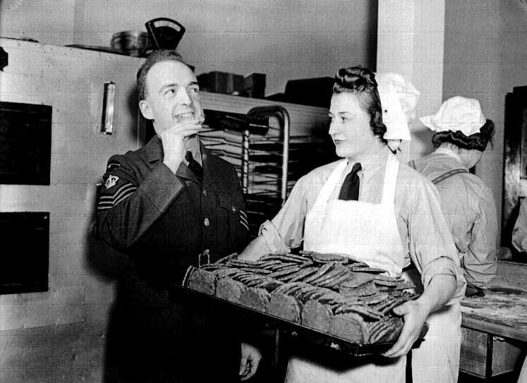 The assistant bakery instructor samples cookies made by a member of the RCAF Women's Division