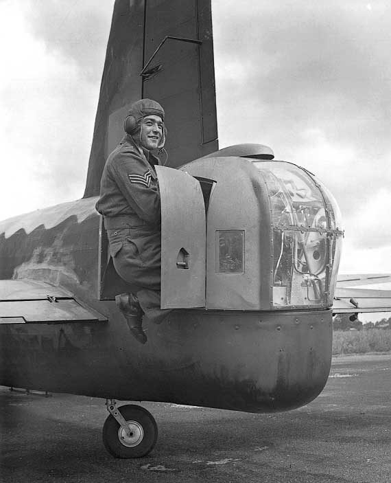 A Flight Sergeant climbs out of a gun turret on the tail of a Wellington after testing his turret mechanism