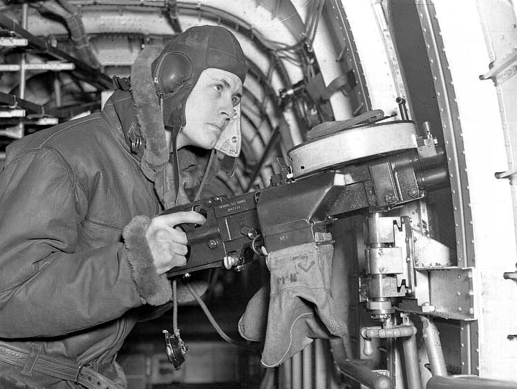 An Air Gunner at the side gun of a four-engine bomber at a Royal Canadian Air Force Bomber Squadron