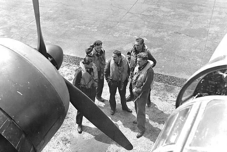 A Royal Canadian Air Force crew framed by the engine and cab of their aircraft