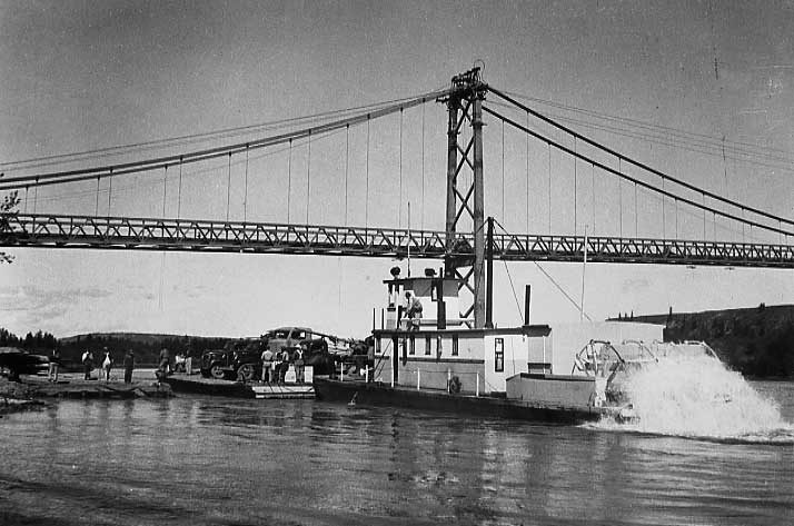A ferry takes trucks across the water under the new Peace River Bridge, built for army truck convoys
