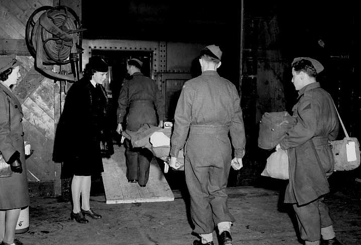 An injured soldier on a stretcher is transported onto a hospital car