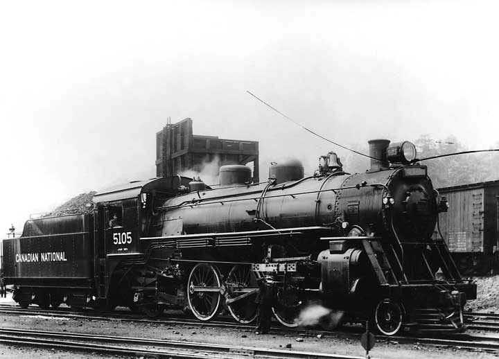 An employee lubricates Canadian National Railways steam locomotive 5105, with an engineer in the cab