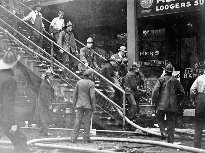Firefighters evacuate injured man during Seattle dock fire at the Grand Trunk Pacific Coast Steamship Company dock