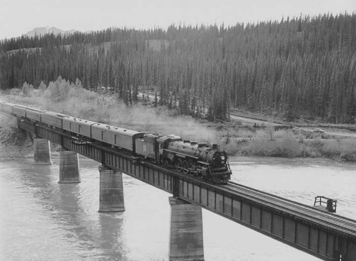 Canadian National Railways steam locomotive no. 6043 hauls a passenger train across the Solomon Creek Bridge