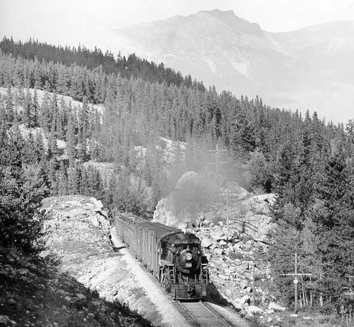 Canadian National Railways steam locomotive no. 5124 hauls a freight train near Roche Bonhomme (Old Man of the Mountain)