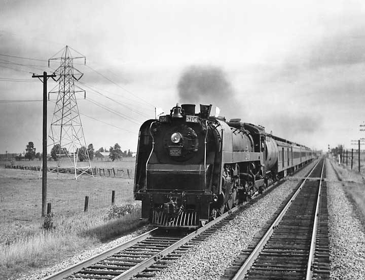 A front view of Canadian National Railways steam locomotive no. 5704 hauling passenger train no. 5 between Montreal and Toronto
