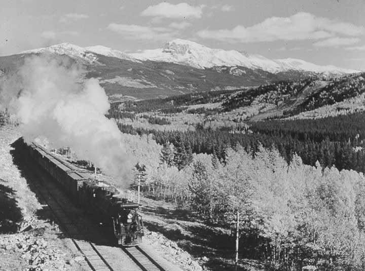 A Canadian National Railways freight train steams through the Canadian Rockies in autumn