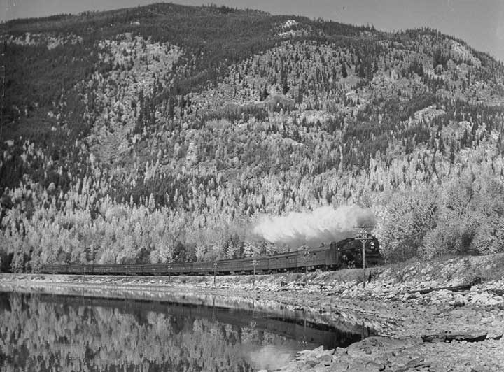 A Canadian National Railways passenger train along the shore of a mountain lake