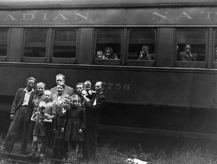 A family of Dutch immigrants poses for the camera in front of a passenger car