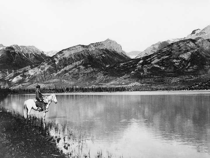 A man on horseback at a mountain lake in Jasper