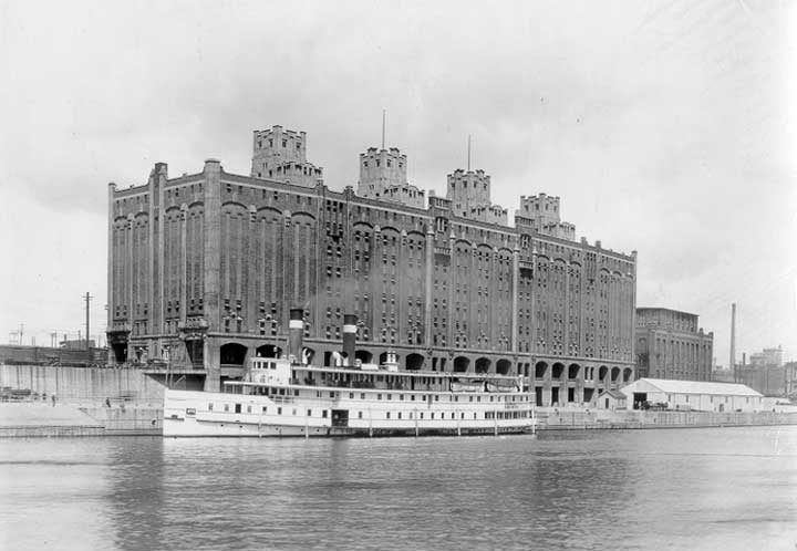 A passenger steamer passes in front of a cold storage plant on the waterfront