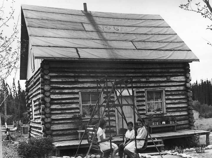 A family relaxing outside their log cabin