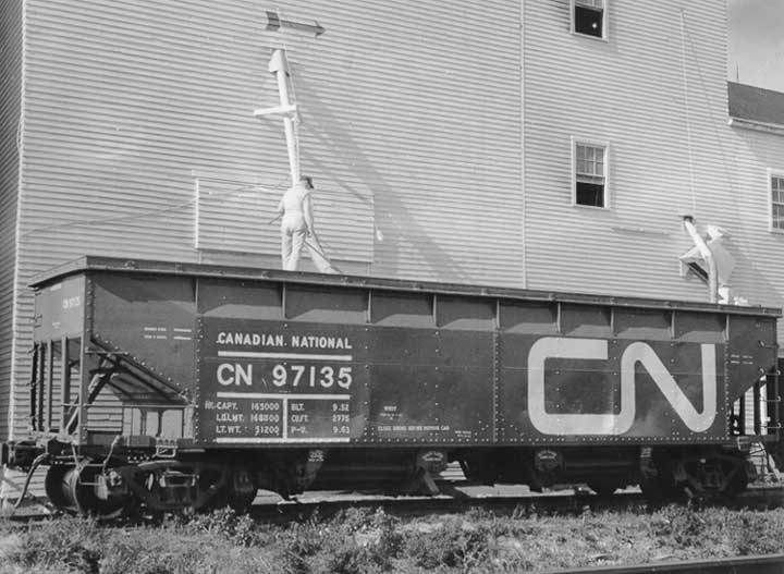 Loading grain from a grain elevator into an open hopper car with a temporary cover