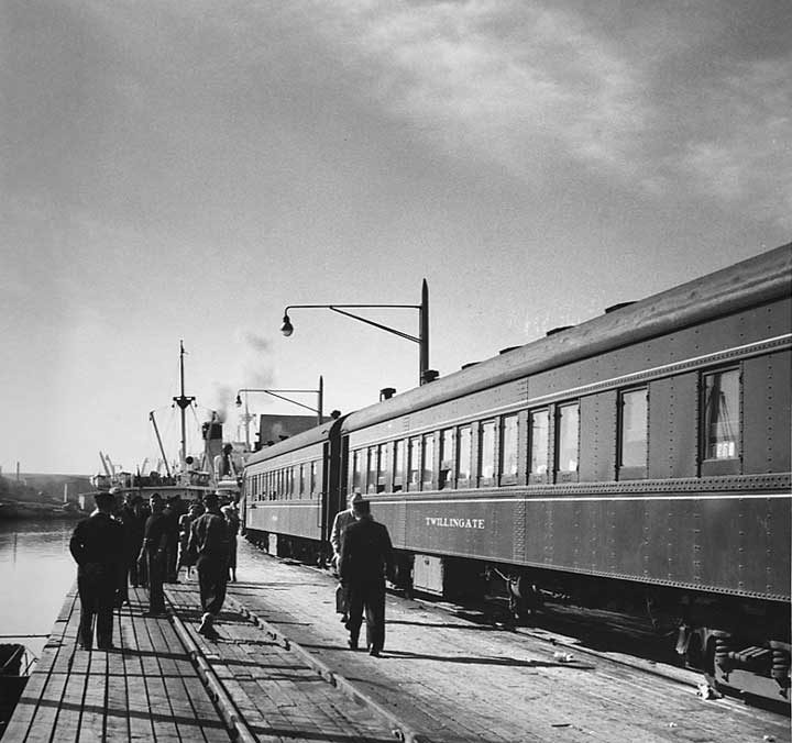 A passenger train and steam ship at the dock