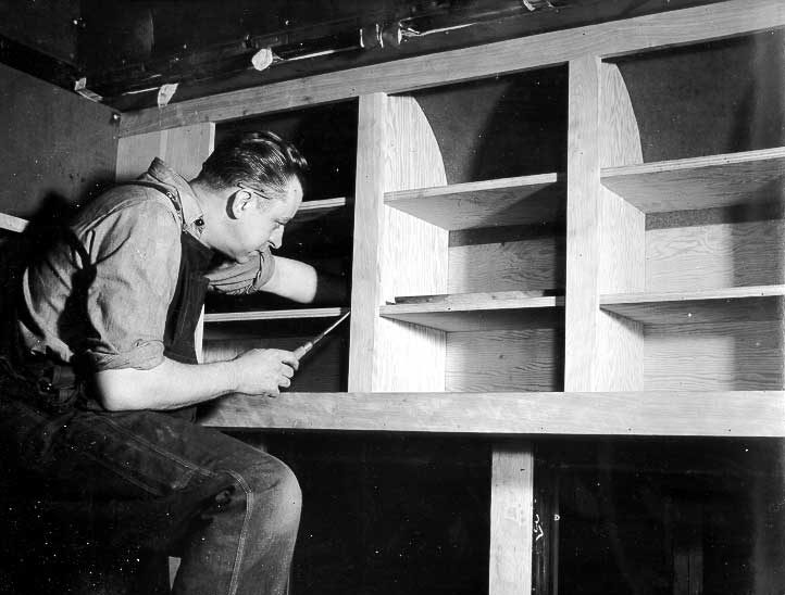 H.E. Thorne, carman, fitting kitchen cupboards in the dental car