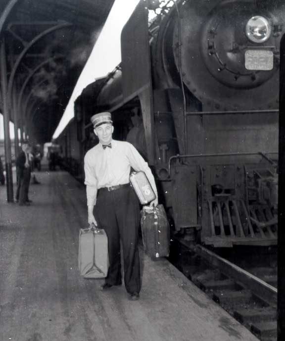 Red cap with luggage next to a steam train, Bonaventure station