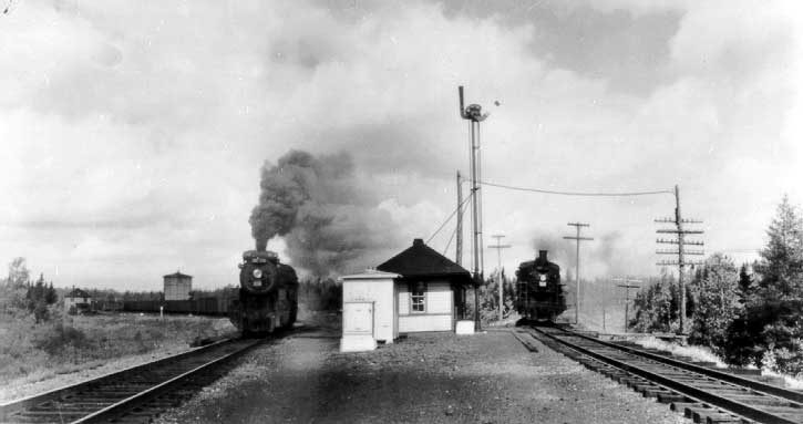 Two steam locomotives passing by centralized traffic control station