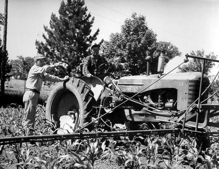 Immigrant workers with crop spraying tractor on a Maple, Ontario farm