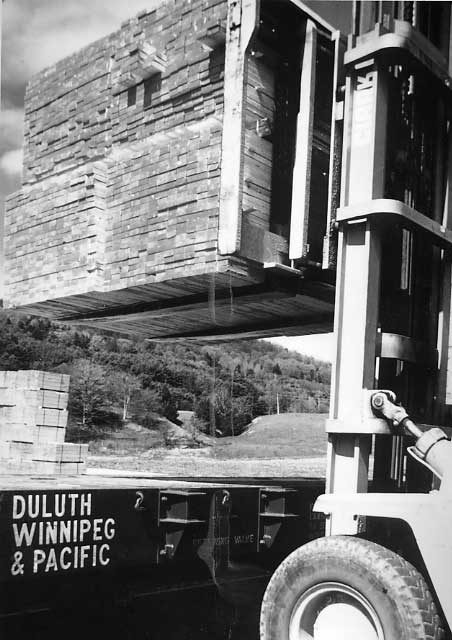 Unloading lumber from a flat car at a lumber distribution yard on the Central Vermont Railway.