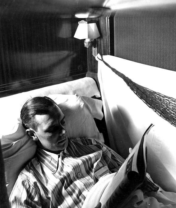 Passenger reading a magazine as he lies in his lower sleeping birth