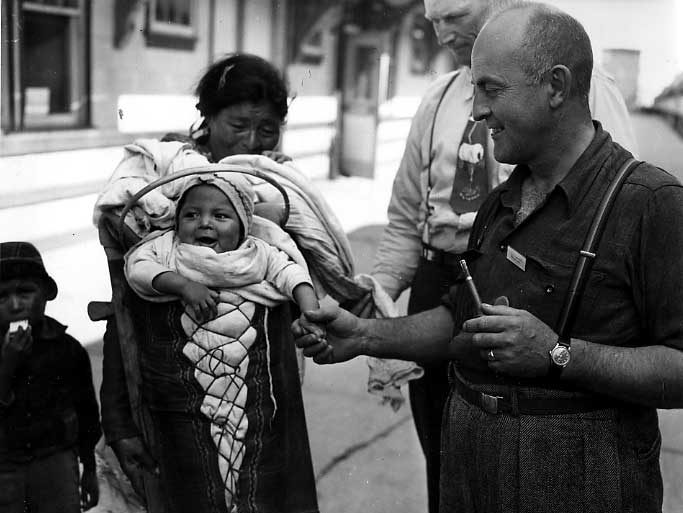 Cree woman and children visited by tourists at a Hudson Bay Railway station