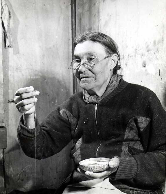 Elderly Kimsquit woman sewing beadwork on moosehide jacket.
Original caption: