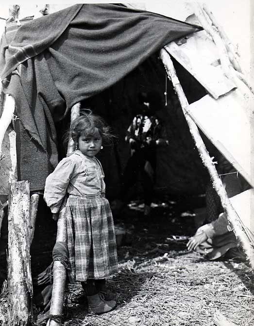 Ojibwa girl at entrance to birch bark wigwam