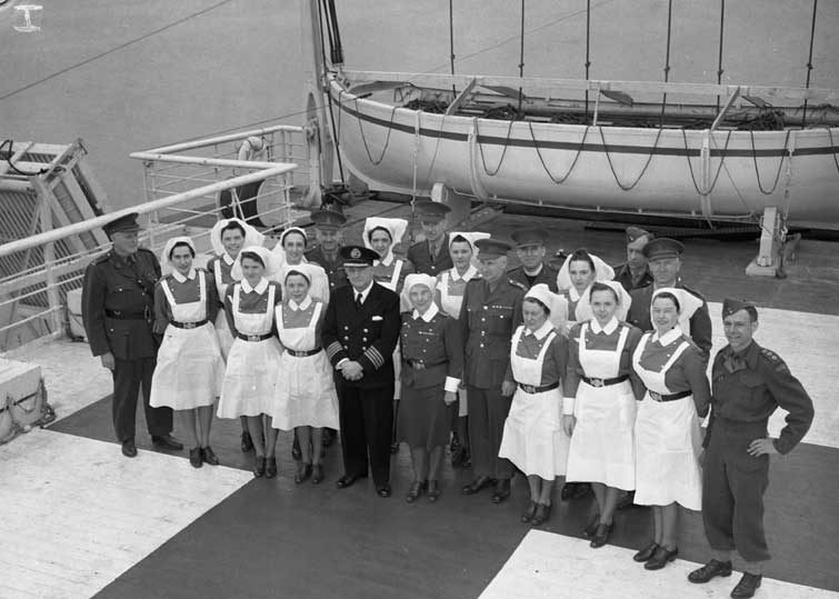 R.C.A.M.C. personnel of the hospital ship. Lady Nelson posing with Captain George W. Welch; Canadian luxury liner sailed under the Red Cross