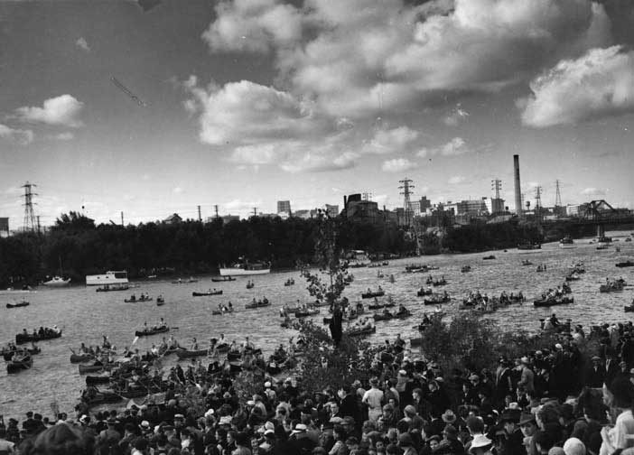 A canoe flotilla on the Red River, as part of the LaVérendrye Parade