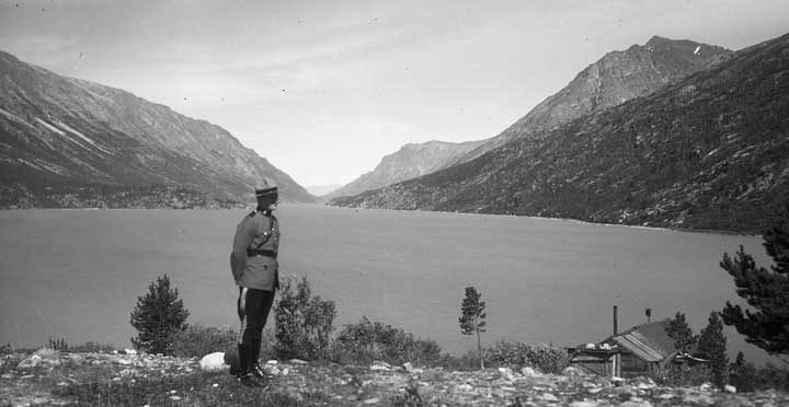 A member of the Royal Canadian Mounted Police standing near Lake Bennett