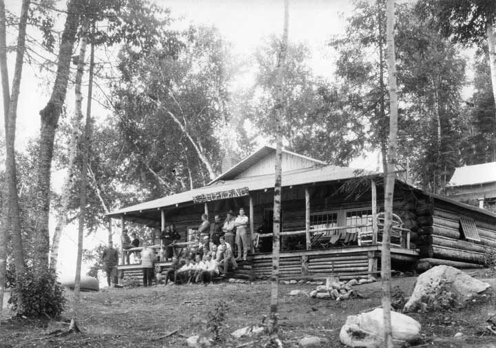 People resting on the porch of a lodge at Acouchiching Camp, Temagami