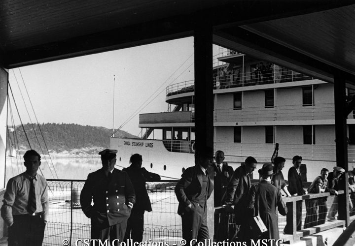 Passengers and crew standing on the dock beside the S.S. Quebec