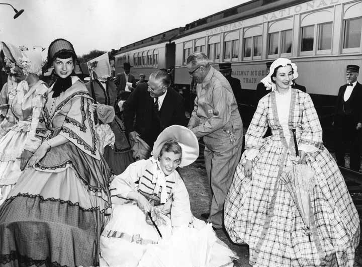 Ontario Premier Leslie Frost putting on coveralls at King Station, Museum Train in the background