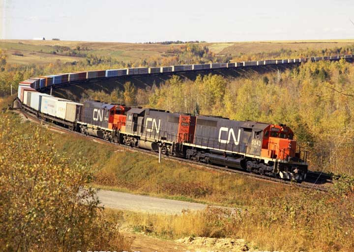 SD40-2 5034 and GP38-2 5532 and 5544 lead container train 208 east bound at Ennishore, NB in 1974