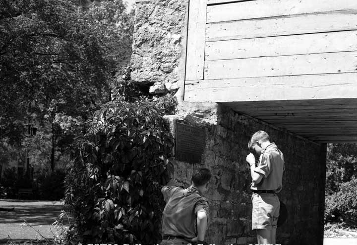 Tourists reading a plaque at the gate to Fort Garry
