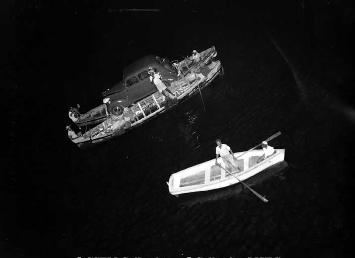 Automobile being transported by canoes to be loaded on the Lady Rodney