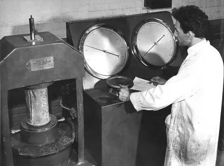 Concrete testing: technician measures force required for failure of concrete cylinder