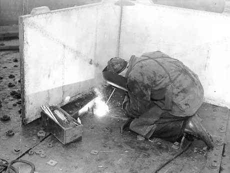 Prince Rupert shipyard : welder at work on deck of 10,000-ton [10 160-tonne] cargo ship under construction