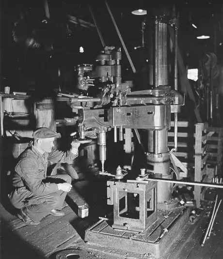 Prince Rupert shipyard : drill press operator drilling steel fitting for cargo vessel in machine shop