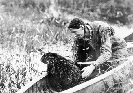 Grey Owl (Archibald Stansfeld Belaney) with beaver in canoe