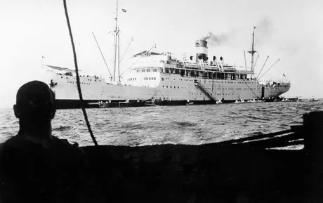 Passengers embarking onto the RMS Lady Drake via small boats